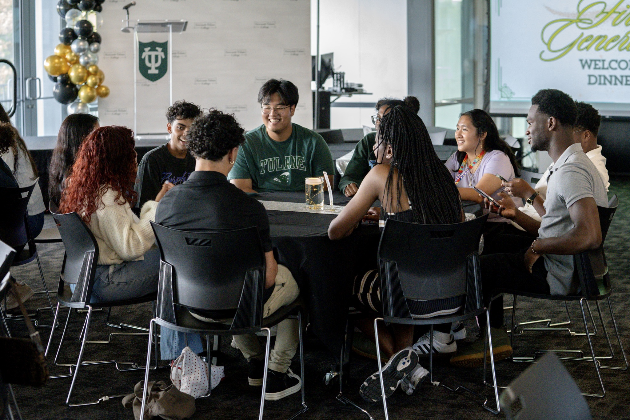 Young adults chat and smile around a table in a modern event space.