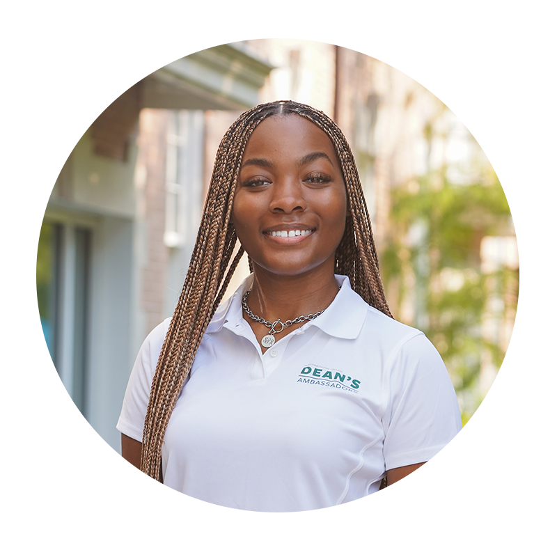 A young woman smiling, wearing a white polo shirt ourdoors