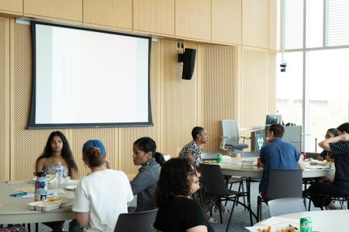 People gathered in a bright room with a blank projector screen.